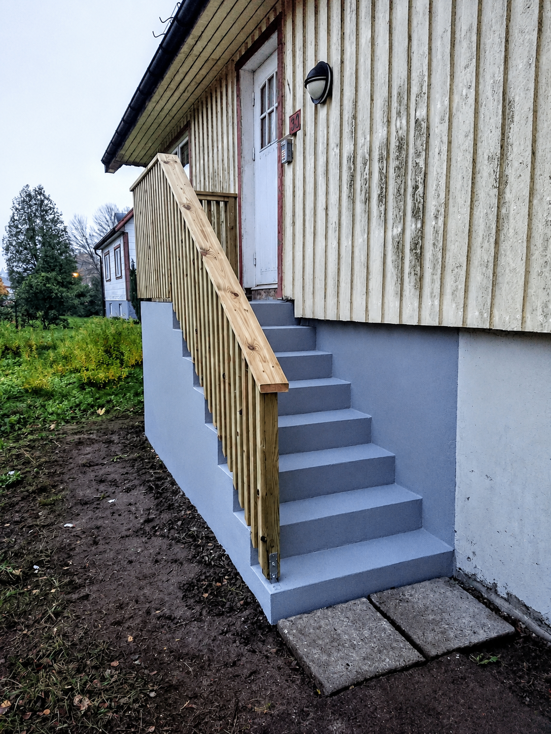 Entrétrappa efter renovering med målade steg och nytt träcke.